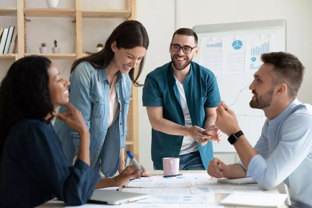Smiling diverse colleagues gather in boardroom brainstorm discuss financial statistics together