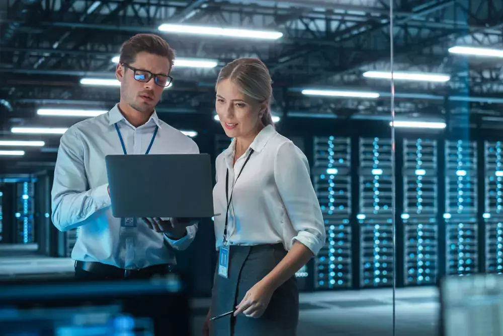 Female chief engineer talks with electronics specialist while working on a laptop